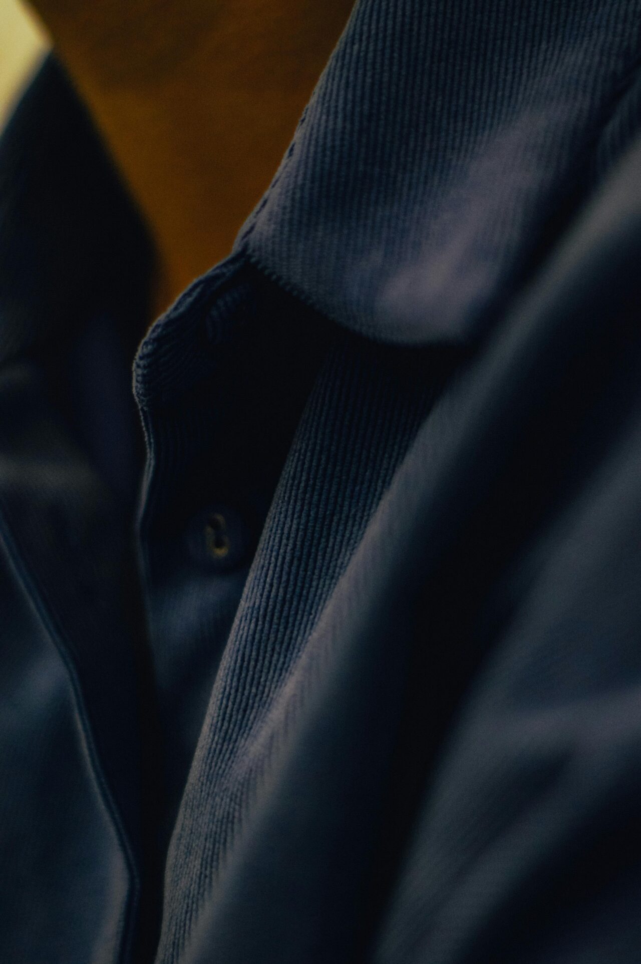 Close-up of a premium navy blue cotton-rich piqué polo shirt collar.