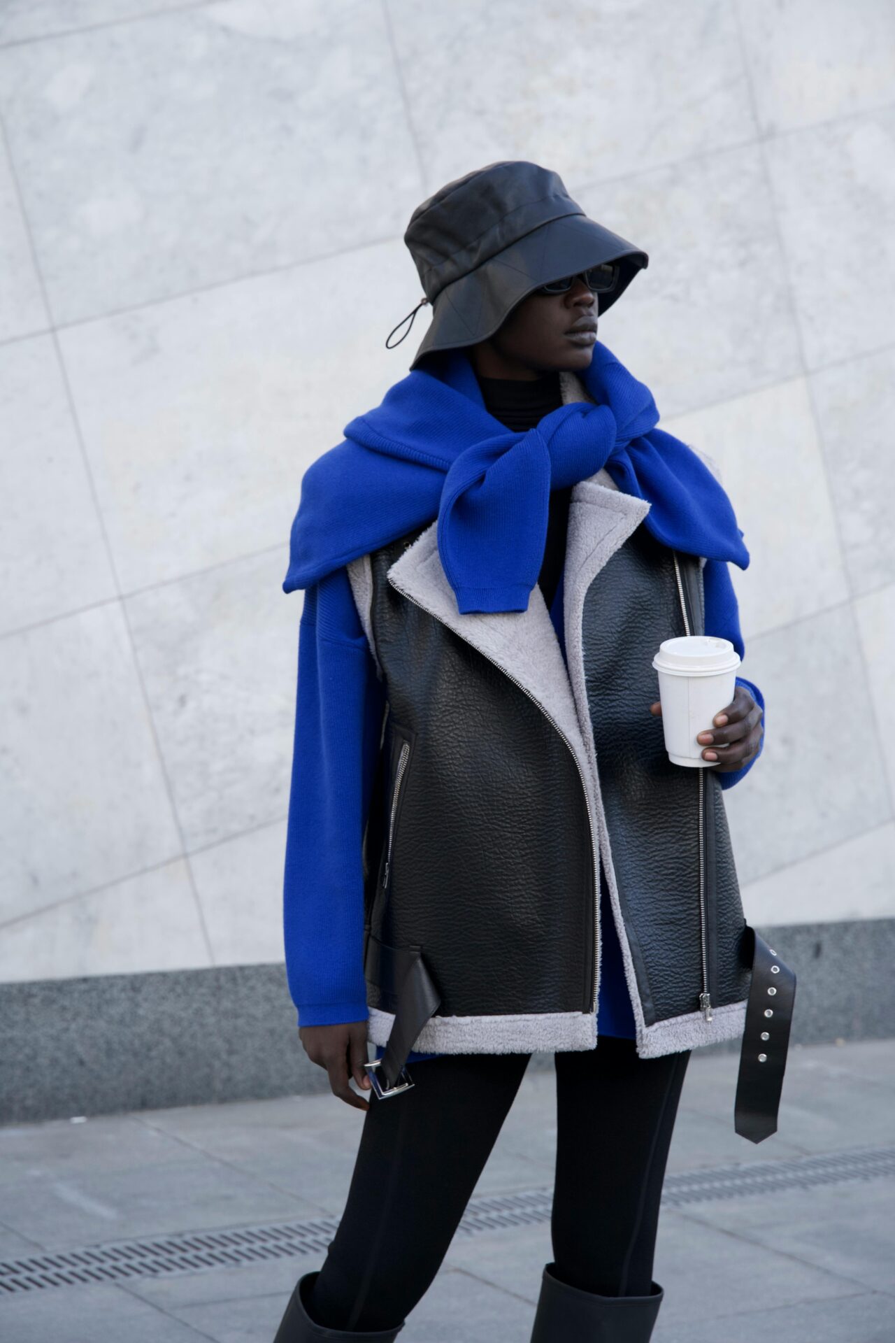 Women's oversized shearling-lined synthetic leather biker vest with contrast blue knitwear.