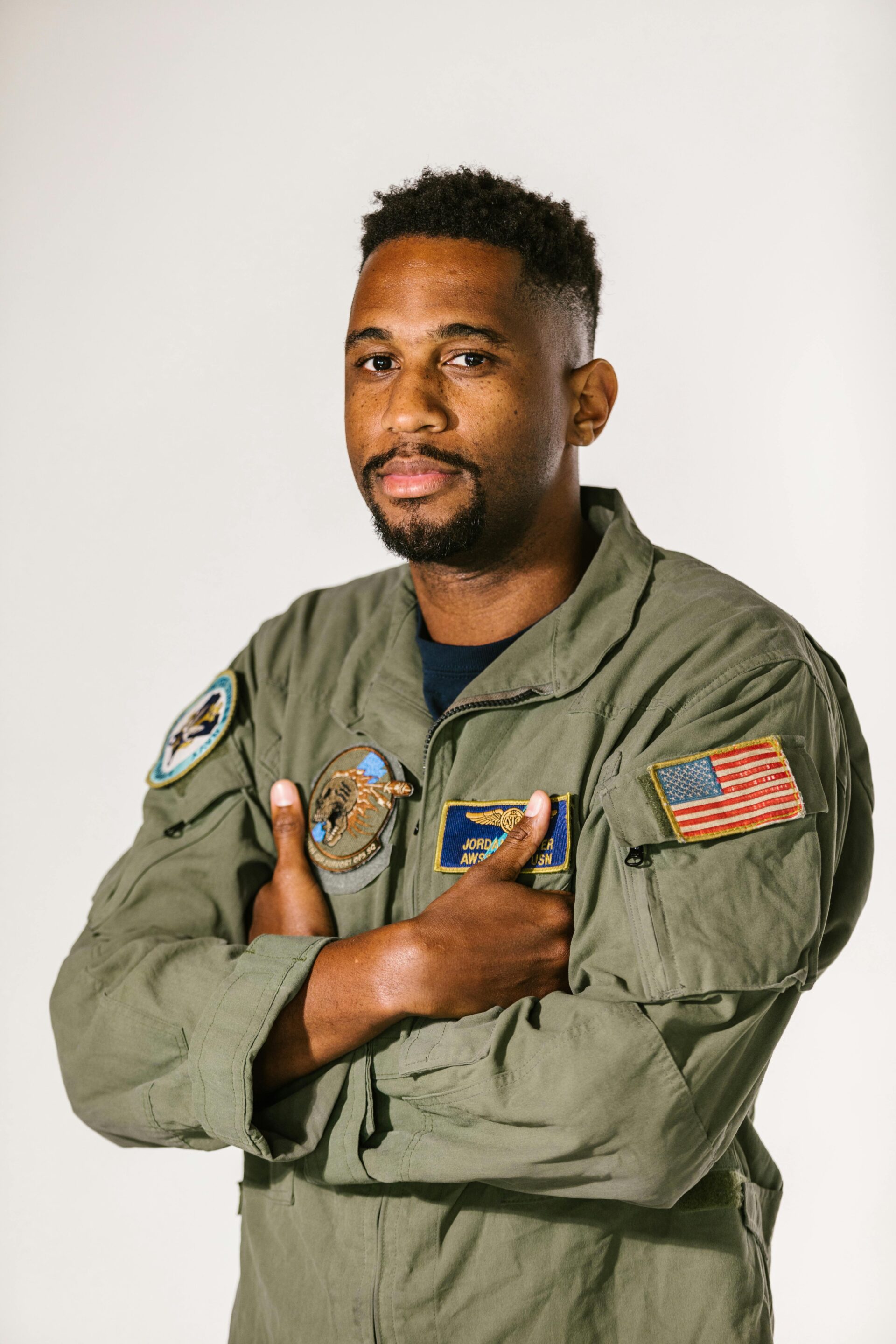 Heavy-duty sage green industrial flight suit and technical coverall with specialized patches.