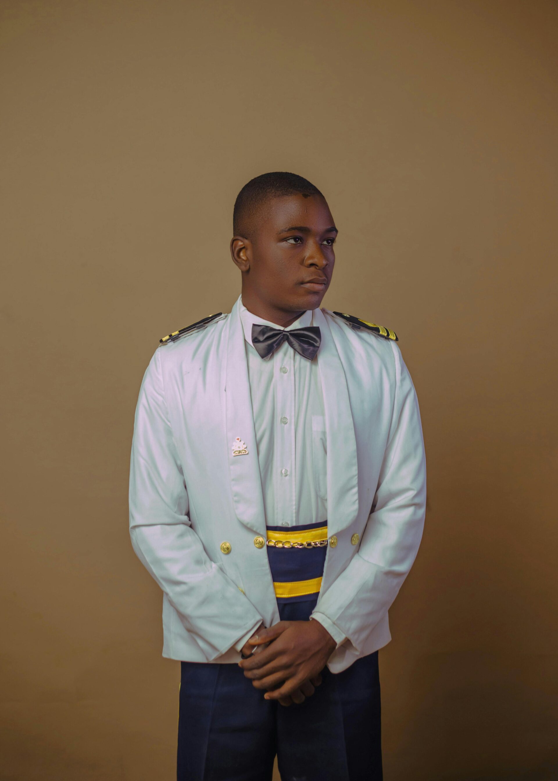 Men's formal white ceremonial gala uniform with black bow tie and contrast waist sash.